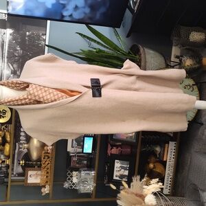 Sleeveless sweater vest with a leather buckle closure.